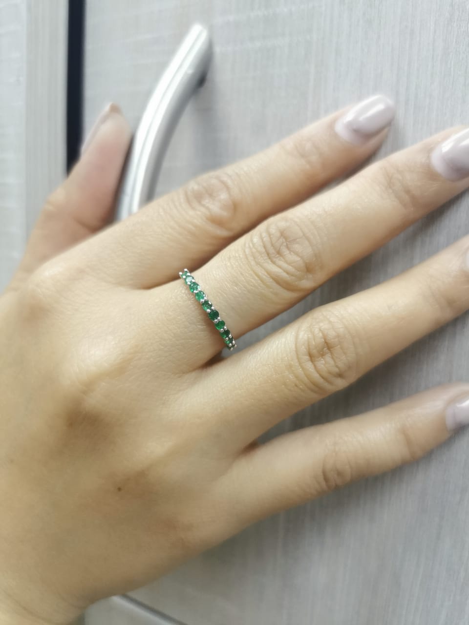 18K gold half-eternity ring with 0.42 carat round-cut emeralds in a prong setting.
