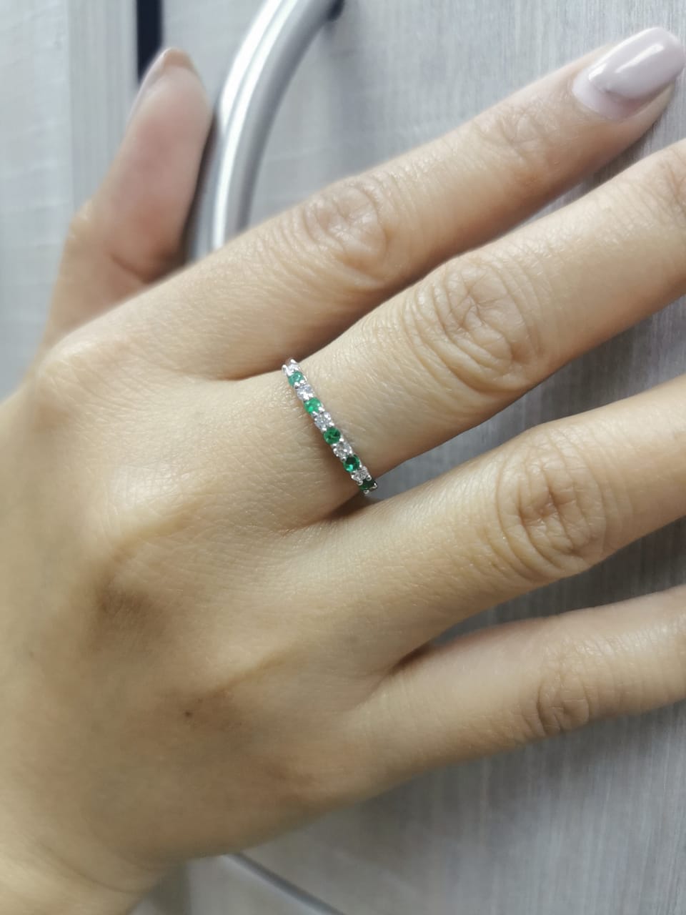 18K white gold half-eternity ring with alternating emeralds and diamonds, stackable wedding band design.