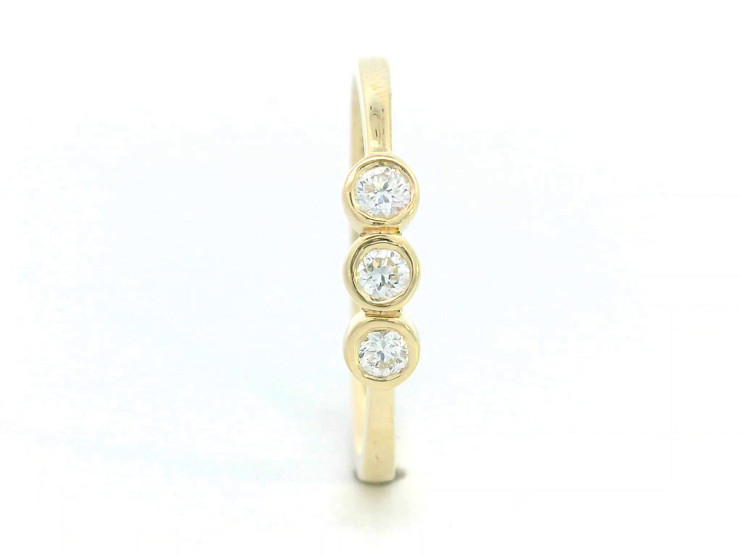 18K yellow gold trilogy ring with 0.18 carat bezel-set round diamonds, minimalist band design.