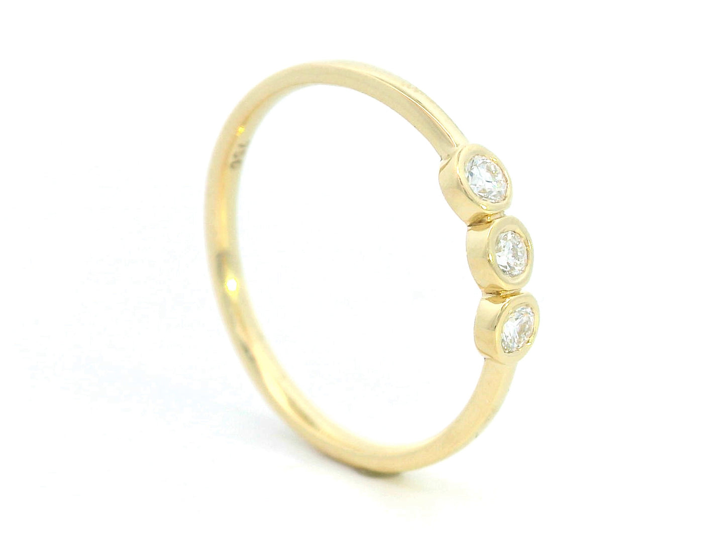 18K yellow gold trilogy ring with 0.18 carat bezel-set round diamonds, minimalist band design.