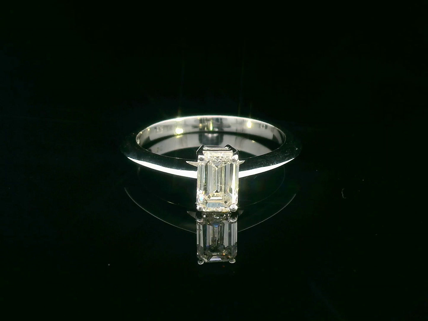 0.91 carat emerald cut diamond solitaire ring with knife-edge 18K gold band, minimalist and elegant design.