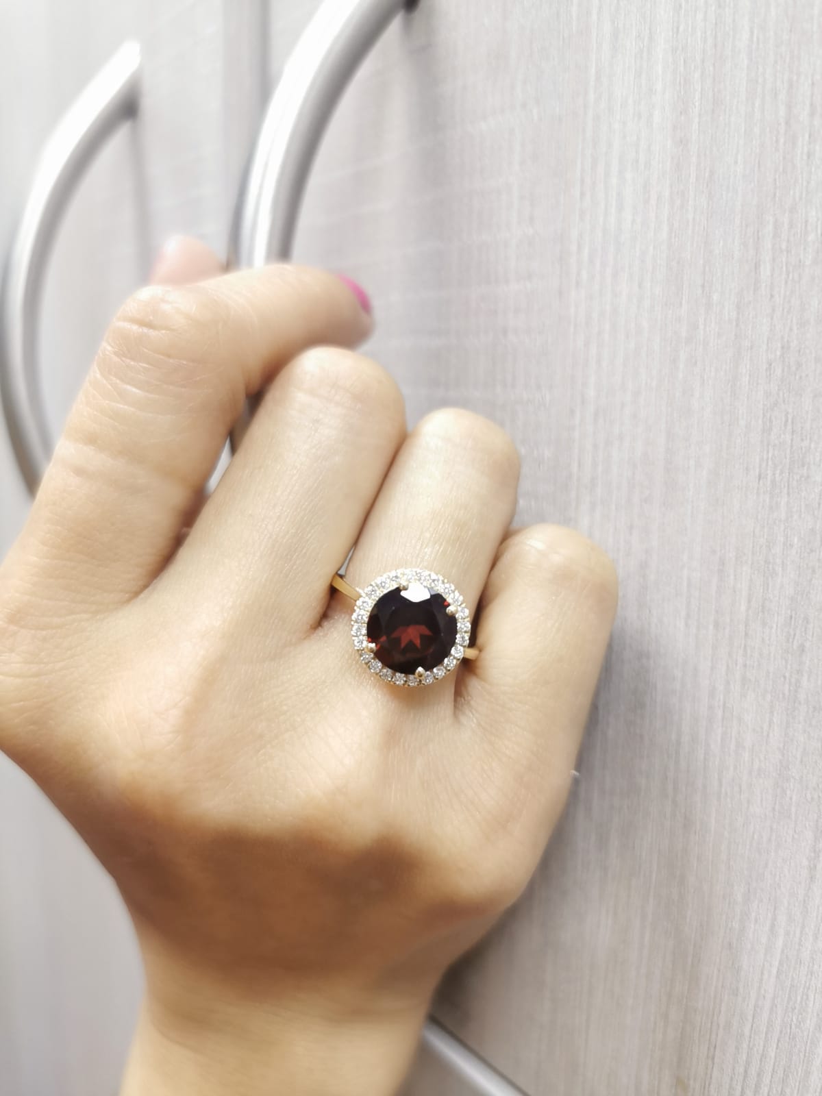 Round garnet and diamond halo ring in 18K yellow gold featuring a 3.85 carat garnet and 0.27 carats of diamonds.