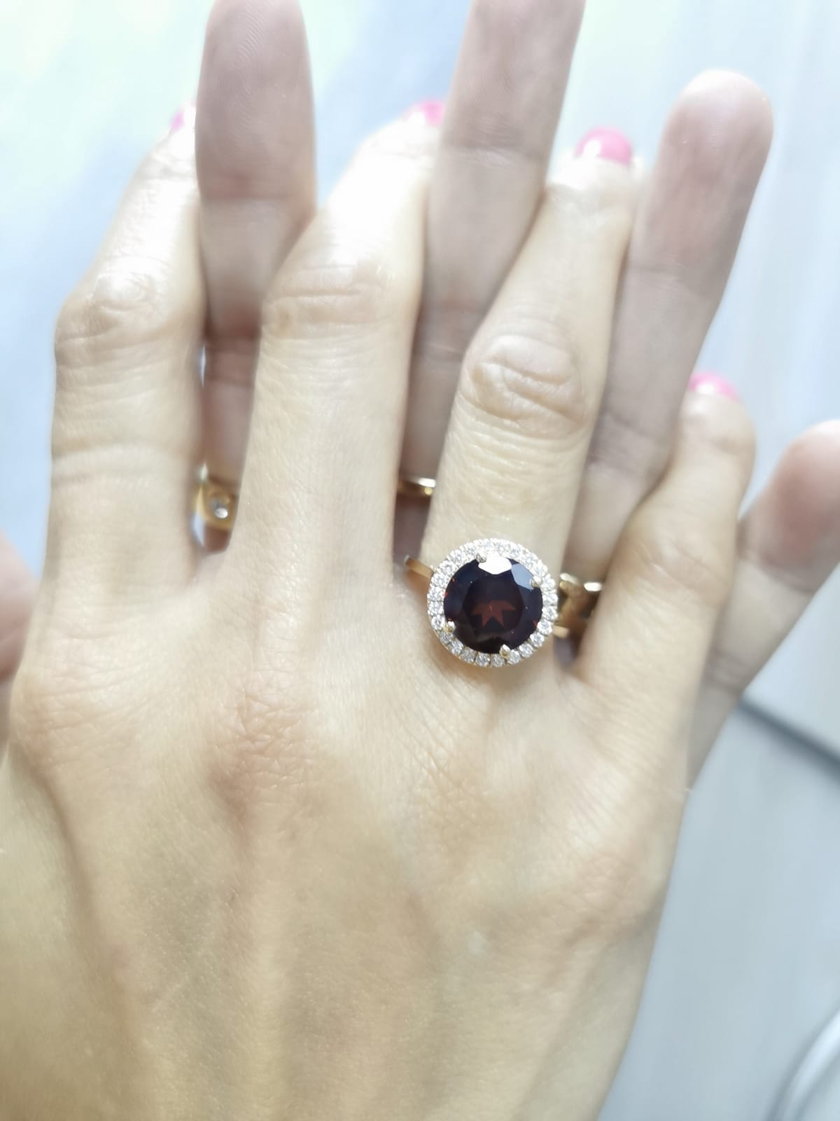 Round garnet and diamond halo ring in 18K yellow gold featuring a 3.85 carat garnet and 0.27 carats of diamonds.