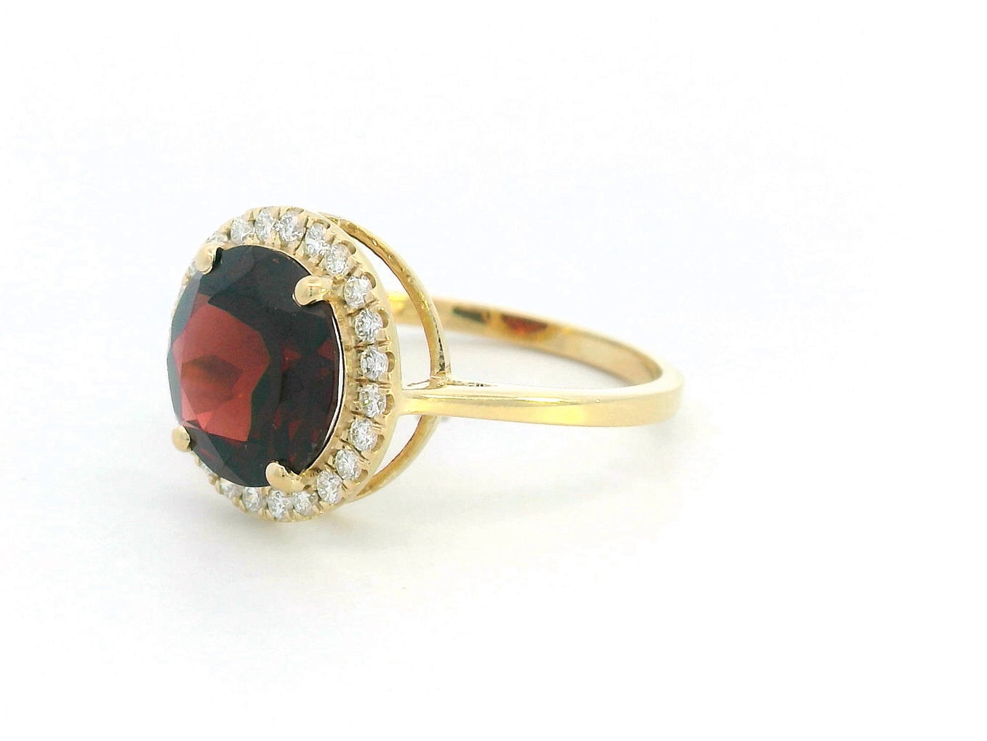 Round garnet and diamond halo ring in 18K yellow gold featuring a 3.85 carat garnet and 0.27 carats of diamonds.