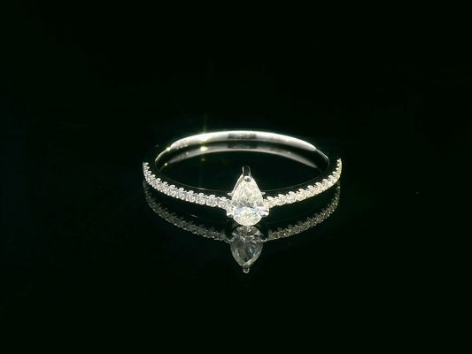 Slim 18K gold ring with pear-shaped diamond and pavé band, minimalist fine jewelry.