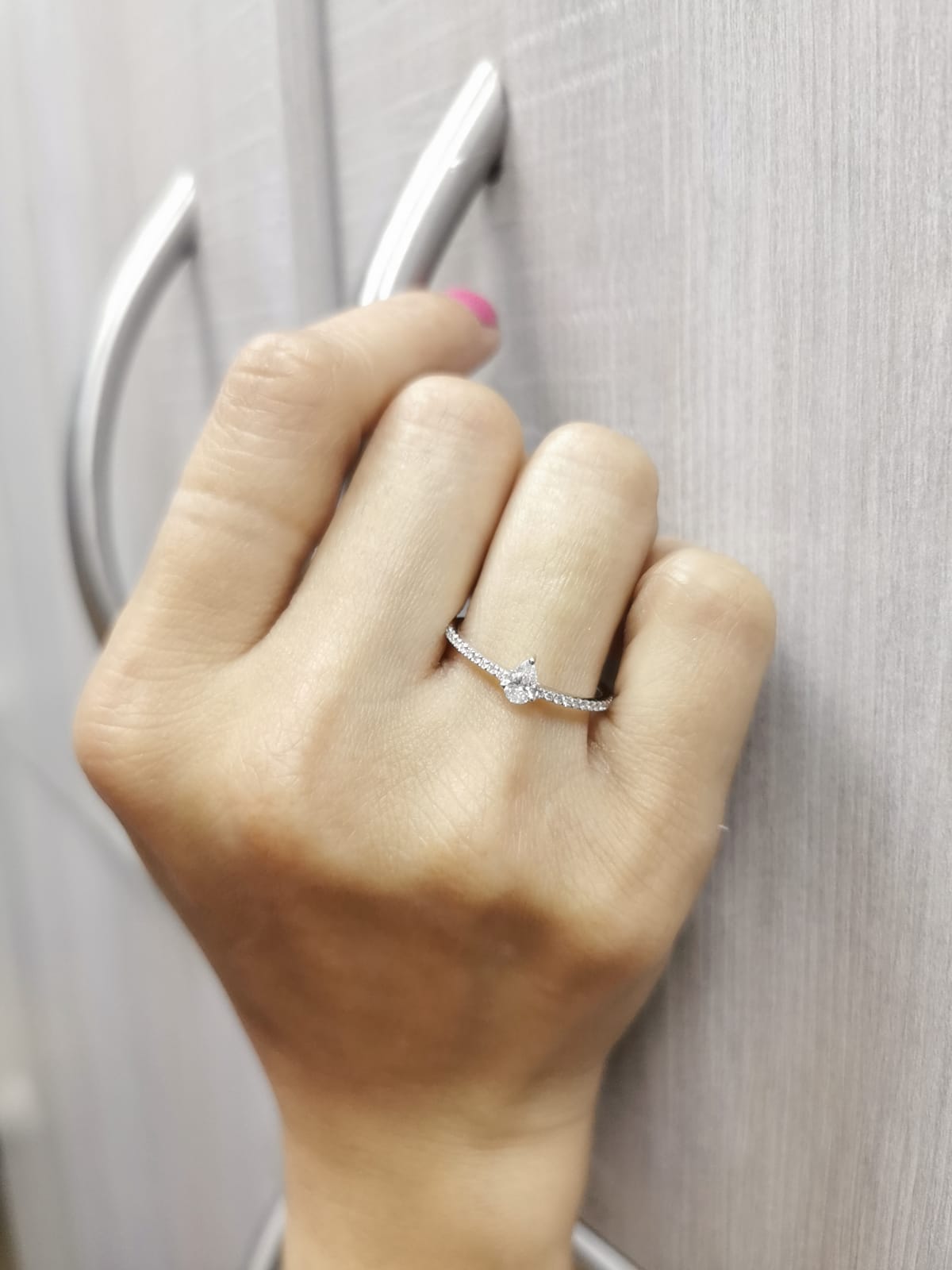 Slim 18K gold ring with pear-shaped diamond and pavé band, minimalist fine jewelry.