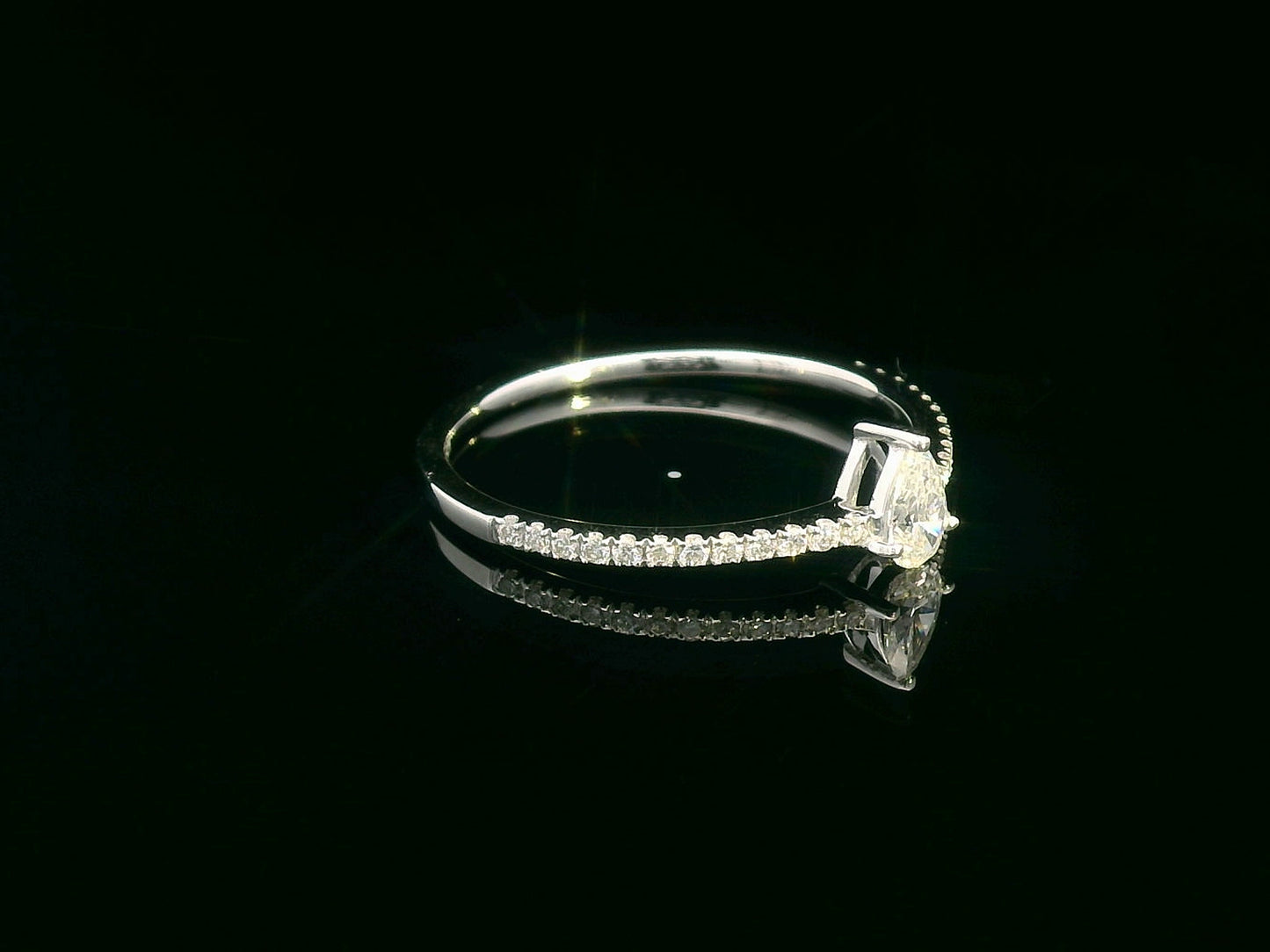 Slim 18K gold ring with pear-shaped diamond and pavé band, minimalist fine jewelry.