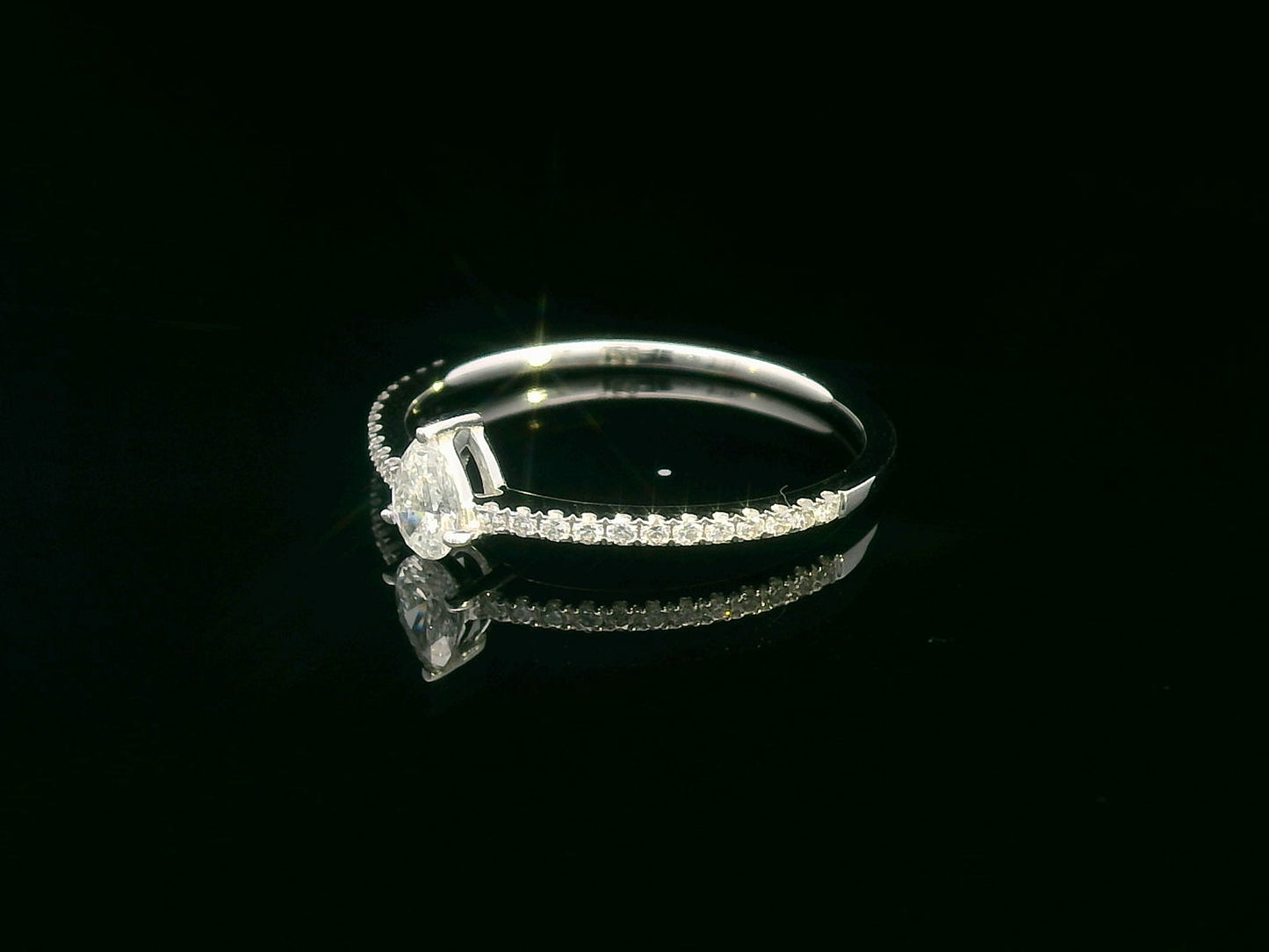Slim 18K gold ring with pear-shaped diamond and pavé band, minimalist fine jewelry.