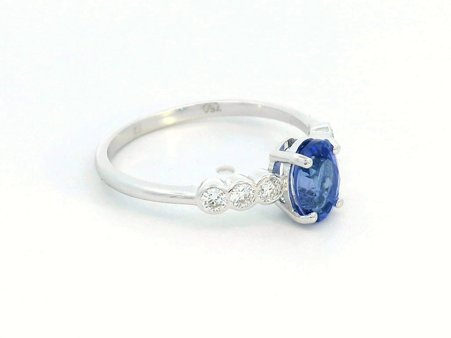 Oval tanzanite and diamond ring in 18K white gold with bezel-set side stones