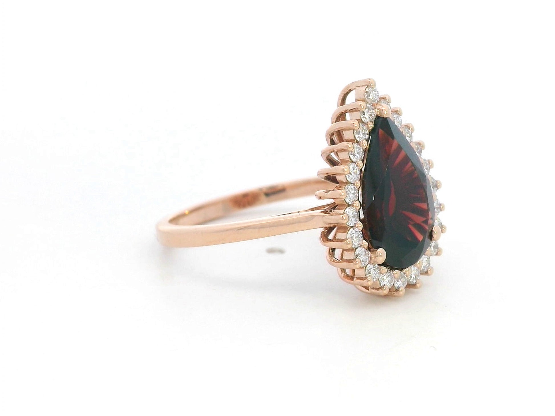 18K rose gold ring with pear-shaped garnet and starburst diamond halo setting