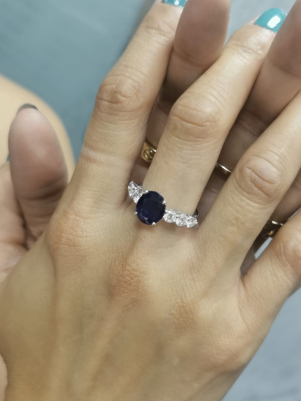 18K white gold ring with oval-cut 2.92ct blue sapphire and round cut diamonds on each side.