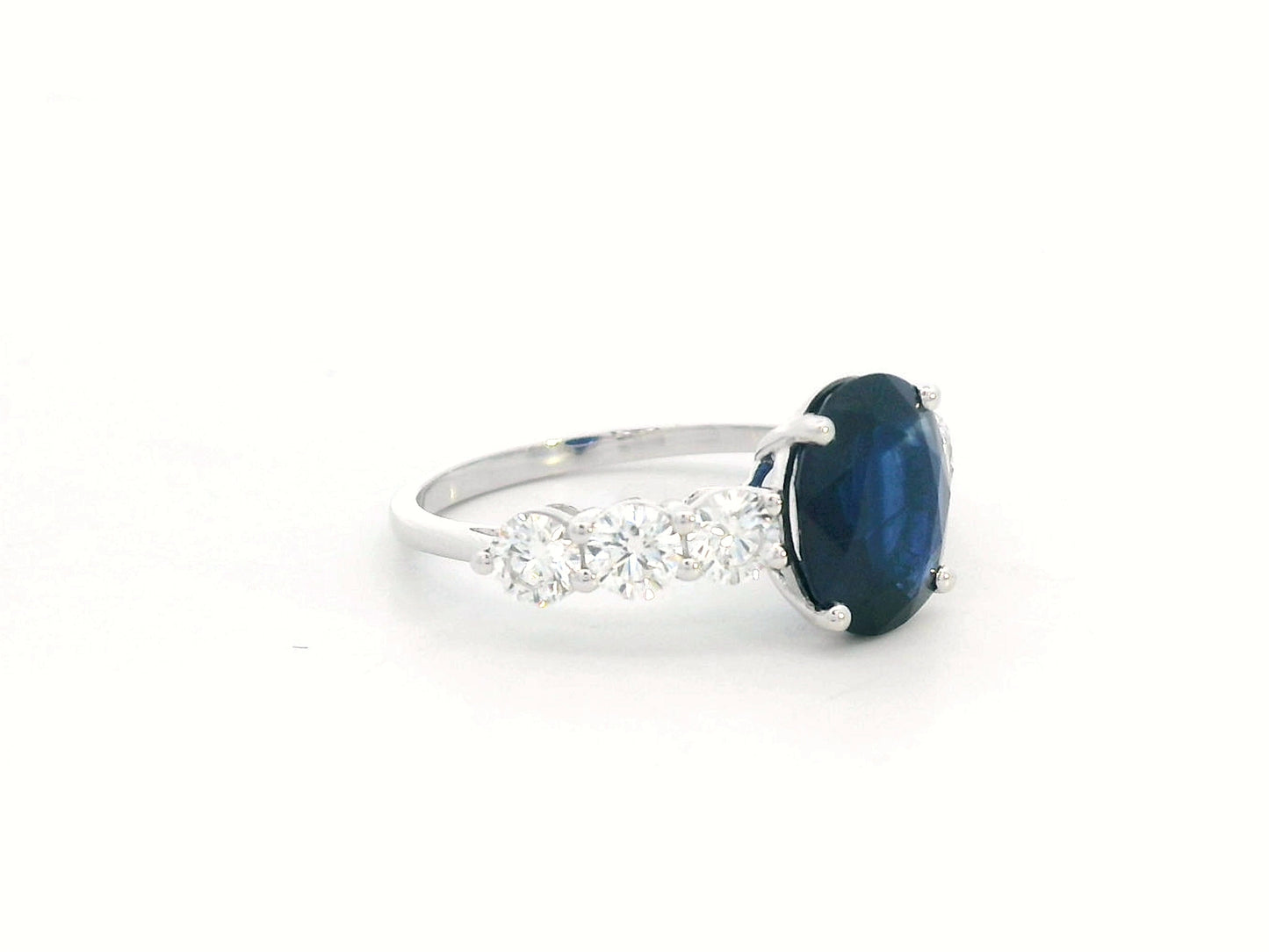 18K white gold ring with oval-cut 2.92ct blue sapphire and round cut diamonds on each side.