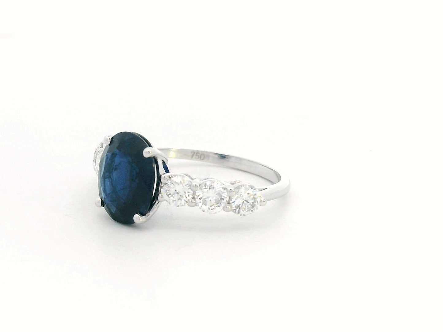 18K white gold ring with oval-cut 2.92ct blue sapphire and round cut diamonds on each side.