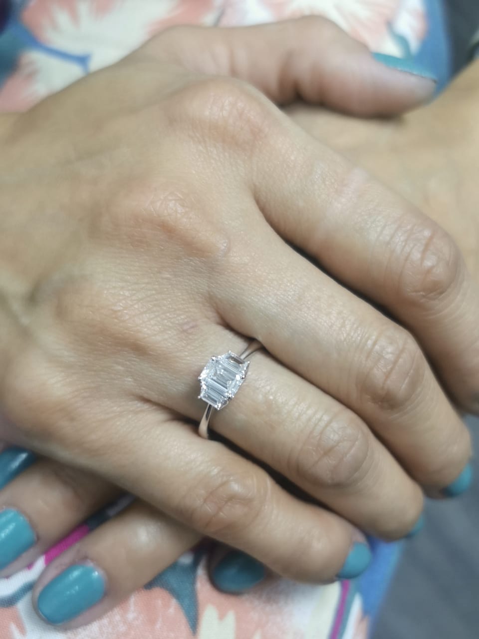Three-stone engagement ring with emerald-cut center diamond and trapezoid side diamonds in 18K gold