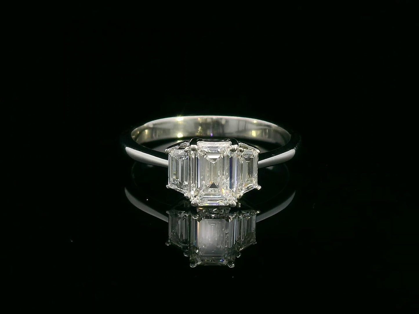 Three-stone engagement ring with emerald-cut center diamond and trapezoid side diamonds in 18K gold