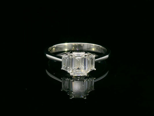 Three-stone engagement ring with emerald-cut center diamond and trapezoid side diamonds in 18K gold