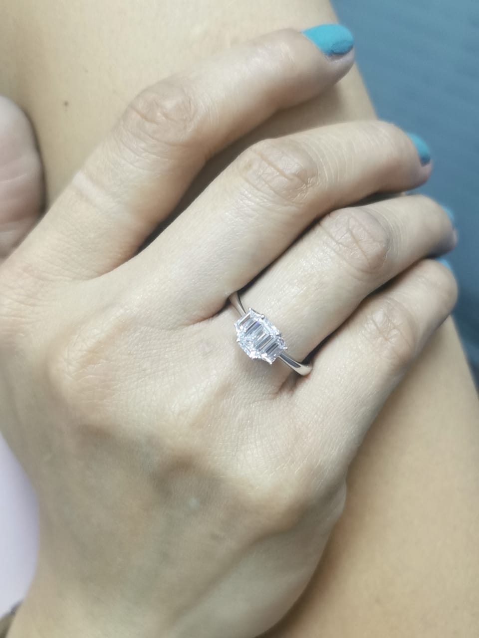 Three-stone engagement ring with emerald-cut center diamond and trapezoid side diamonds in 18K gold
