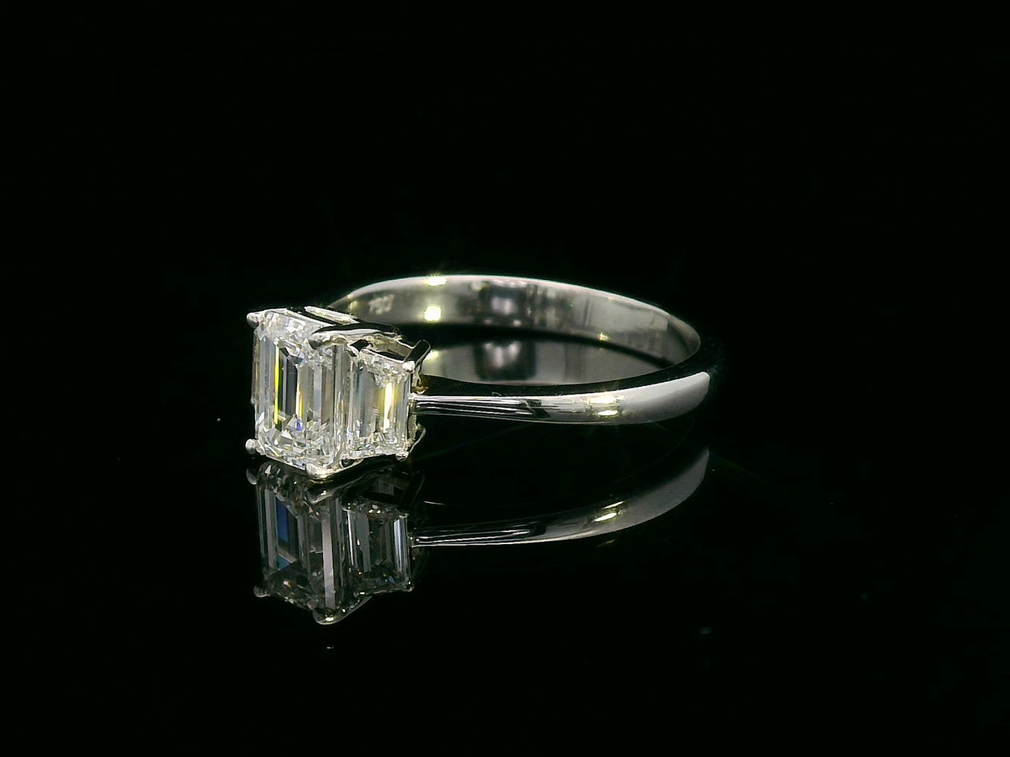 Three-stone engagement ring with emerald-cut center diamond and trapezoid side diamonds in 18K gold