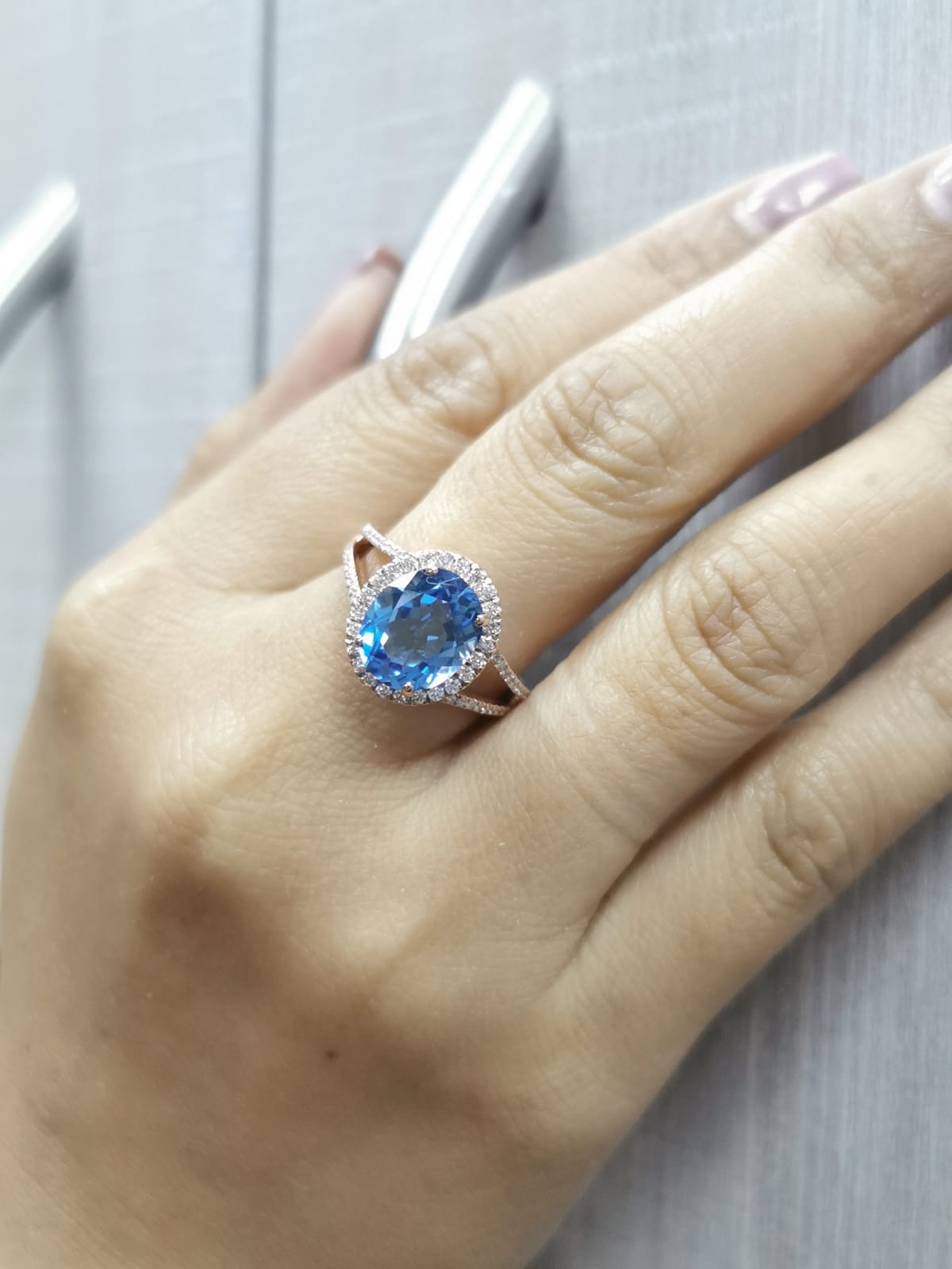 18K rose gold ring with a 4.54 carat oval Swiss Blue Topaz, diamond halo, and diamond-accented split shank design