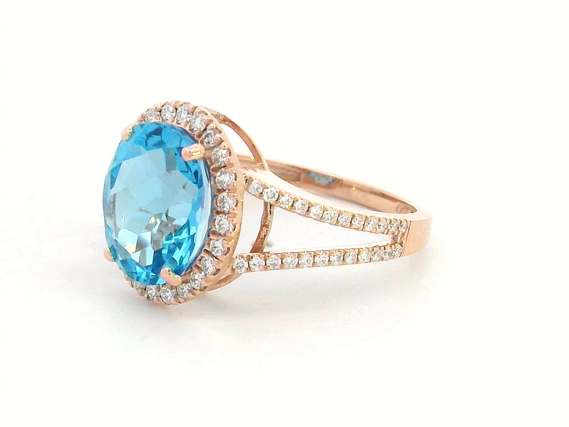 18K rose gold ring with a 4.54 carat oval Swiss Blue Topaz, diamond halo, and diamond-accented split shank design