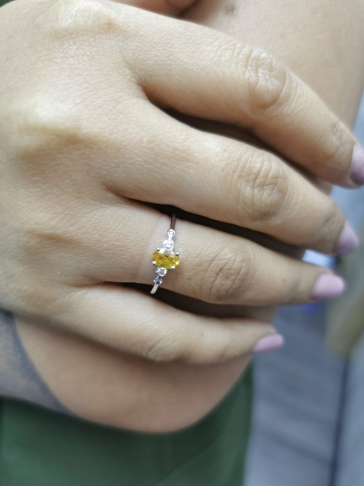 18K gold ring with 0.48ct oval yellow sapphire and two bezel-set round diamonds on a polished band.