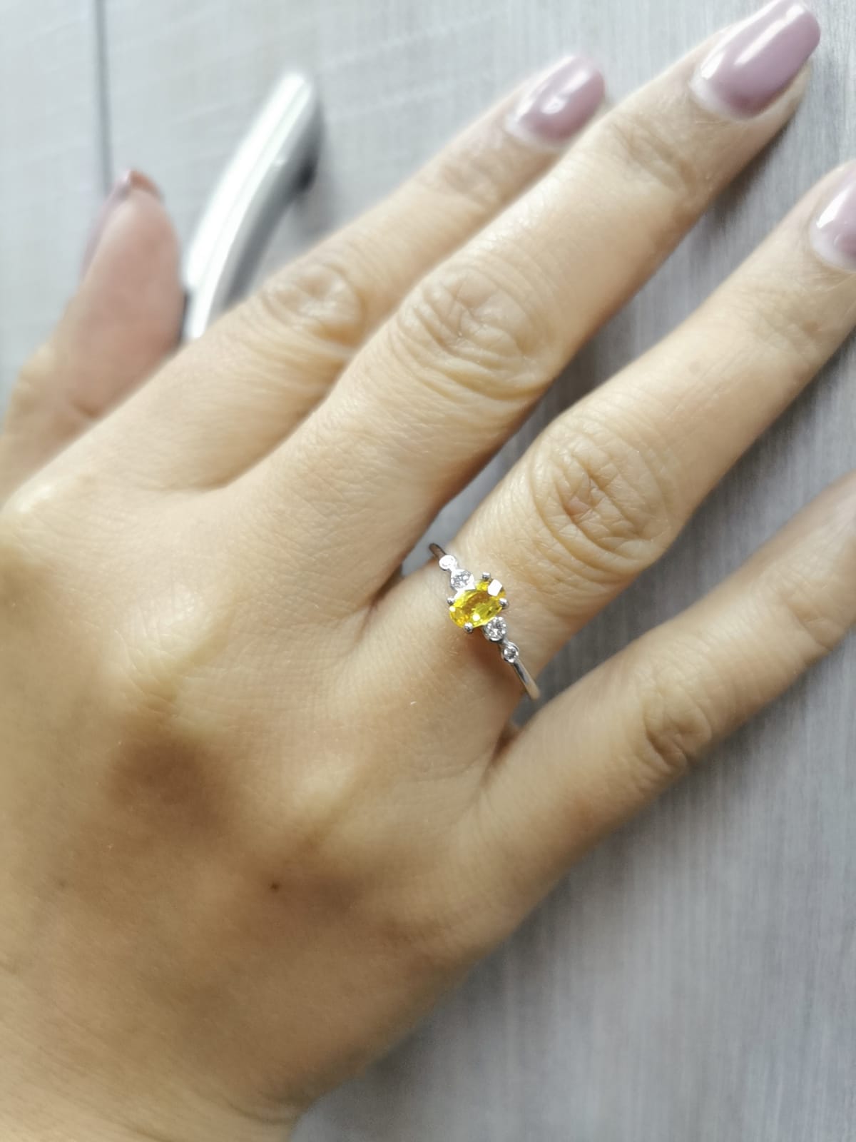 18K gold ring with 0.48ct oval yellow sapphire and two bezel-set round diamonds on a polished band.