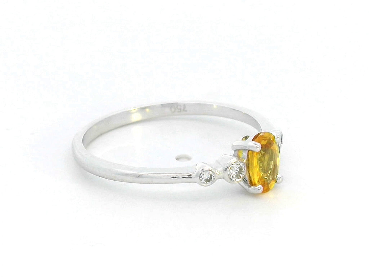 18K gold ring with 0.48ct oval yellow sapphire and two bezel-set round diamonds on a polished band.