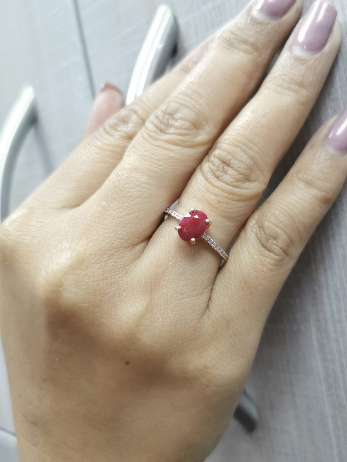 18K rose gold ring featuring a 1.92 carat oval-cut ruby with diamond band