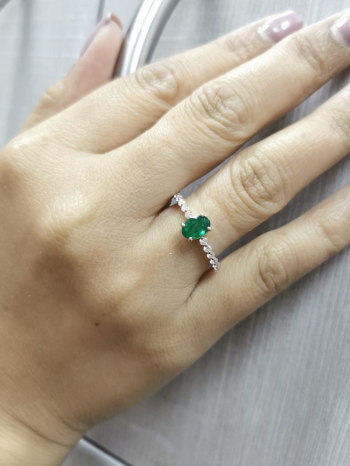 18K yellow gold ring with oval-cut emerald center and round diamond accents on the band