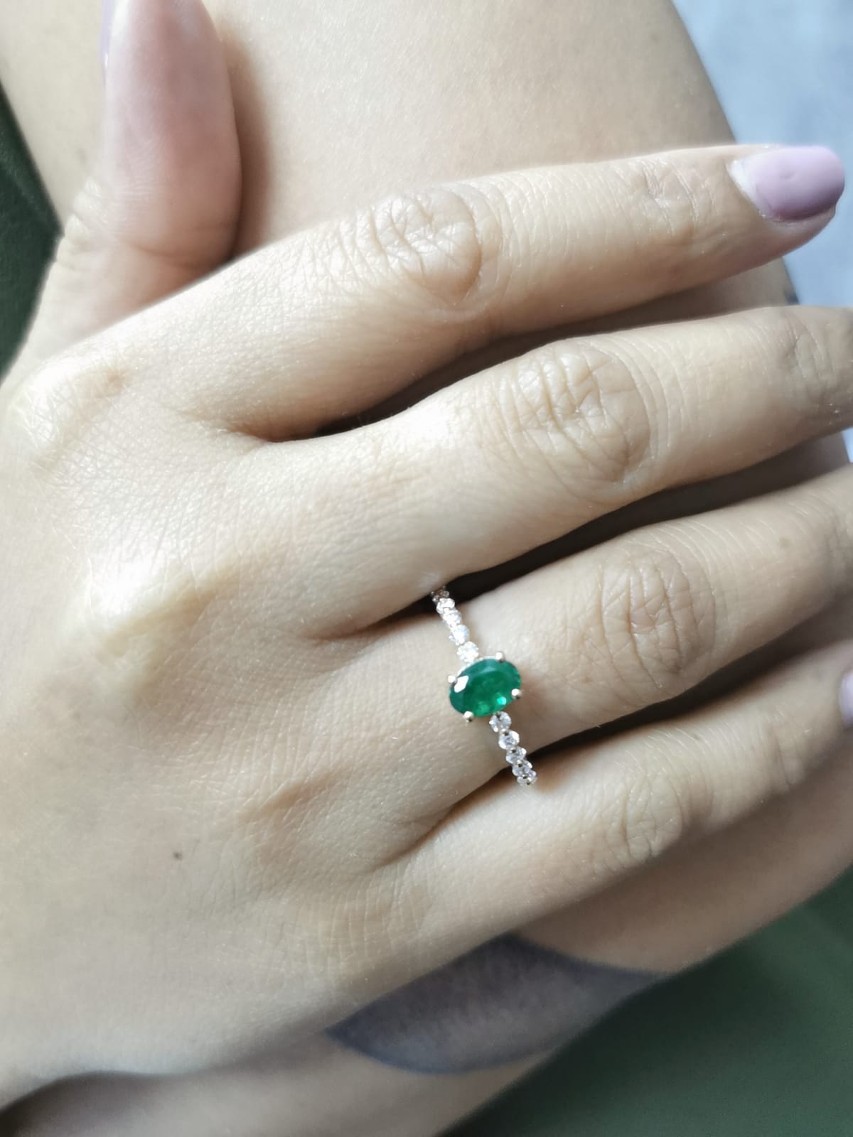 18K yellow gold ring with oval-cut emerald center and round diamond accents on the band