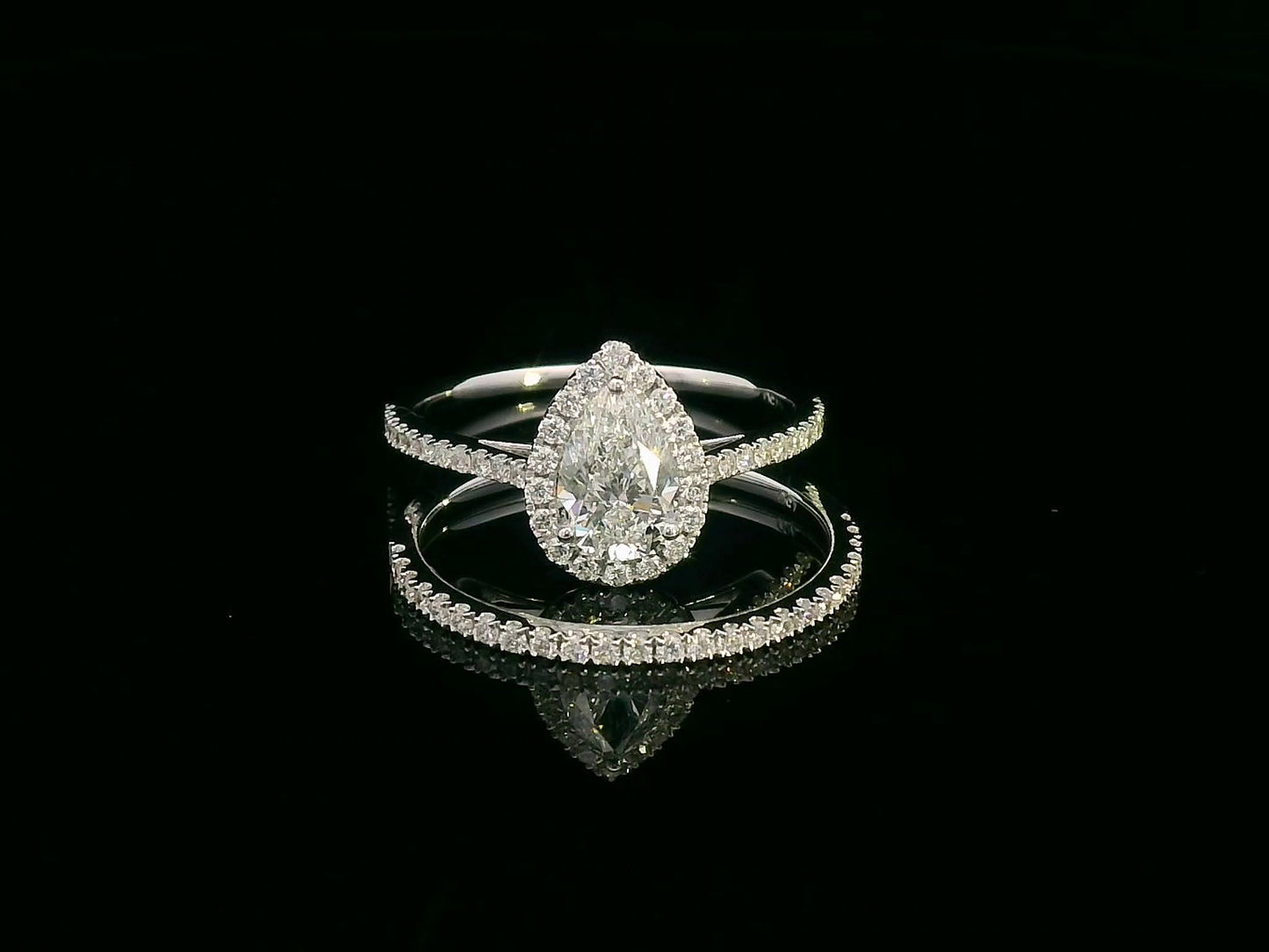18K gold bridal ring set featuring a 0.91 carat pear-shaped diamond with halo and pavé-set accent diamonds on both engagement ring and matching wedding band