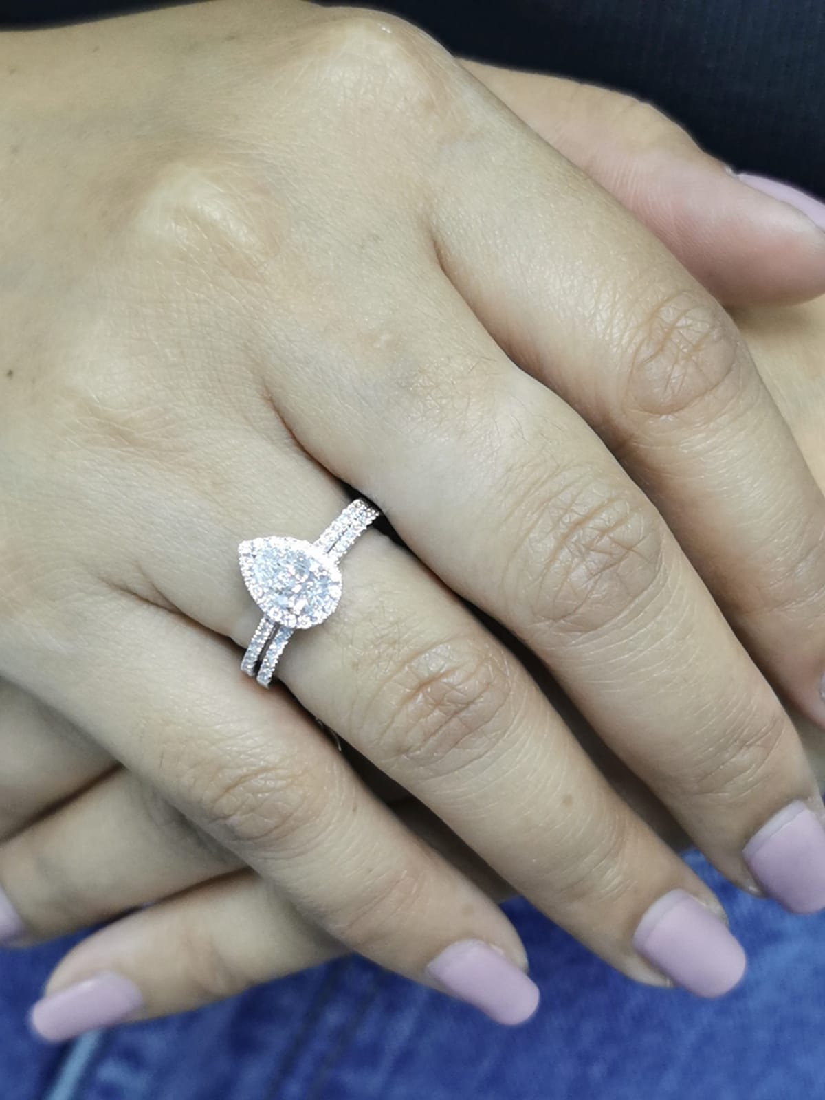 18K gold bridal ring set featuring a 0.91 carat pear-shaped diamond with halo and pavé-set accent diamonds on both engagement ring and matching wedding band