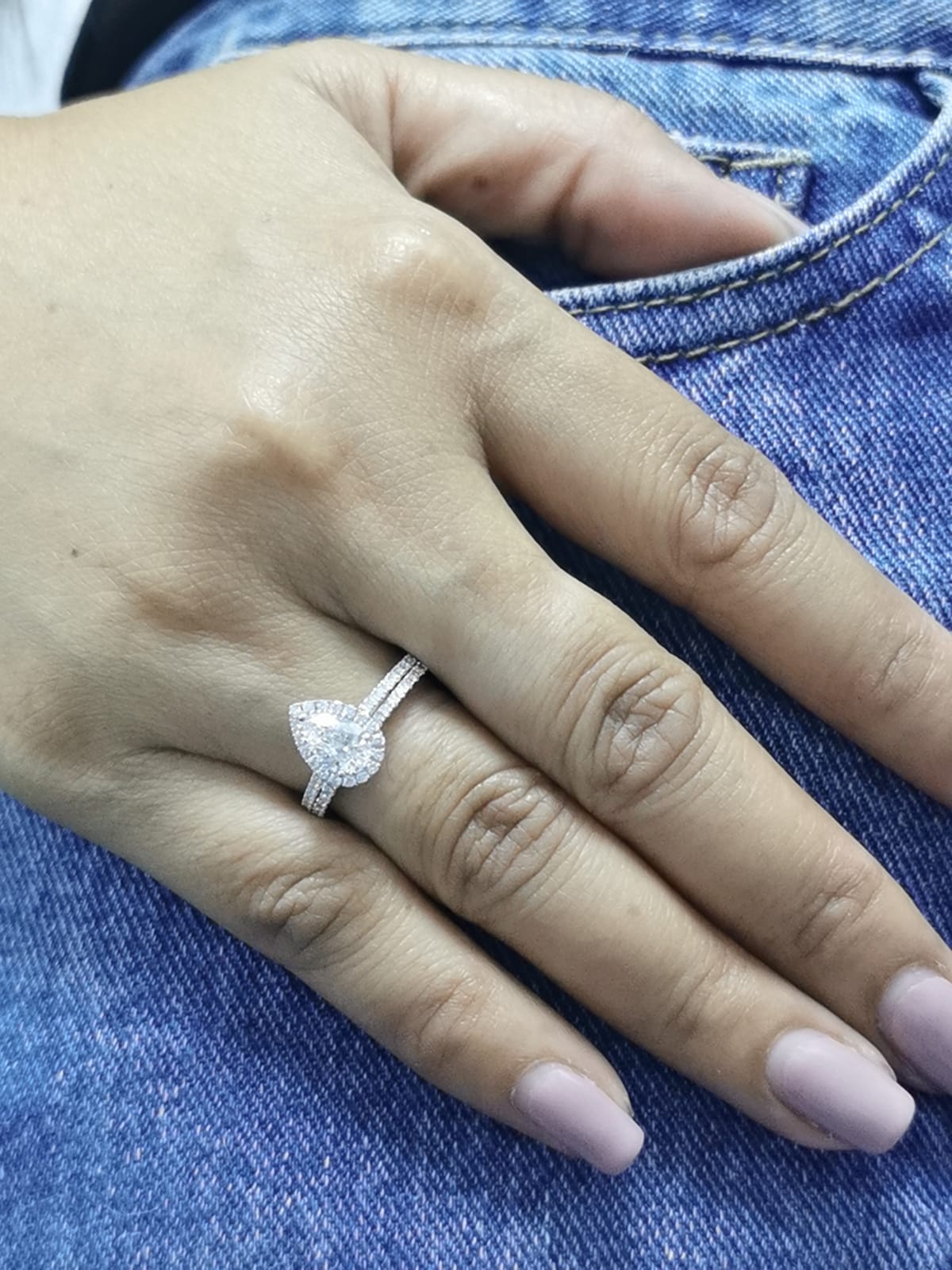 18K gold bridal ring set featuring a 0.91 carat pear-shaped diamond with halo and pavé-set accent diamonds on both engagement ring and matching wedding band