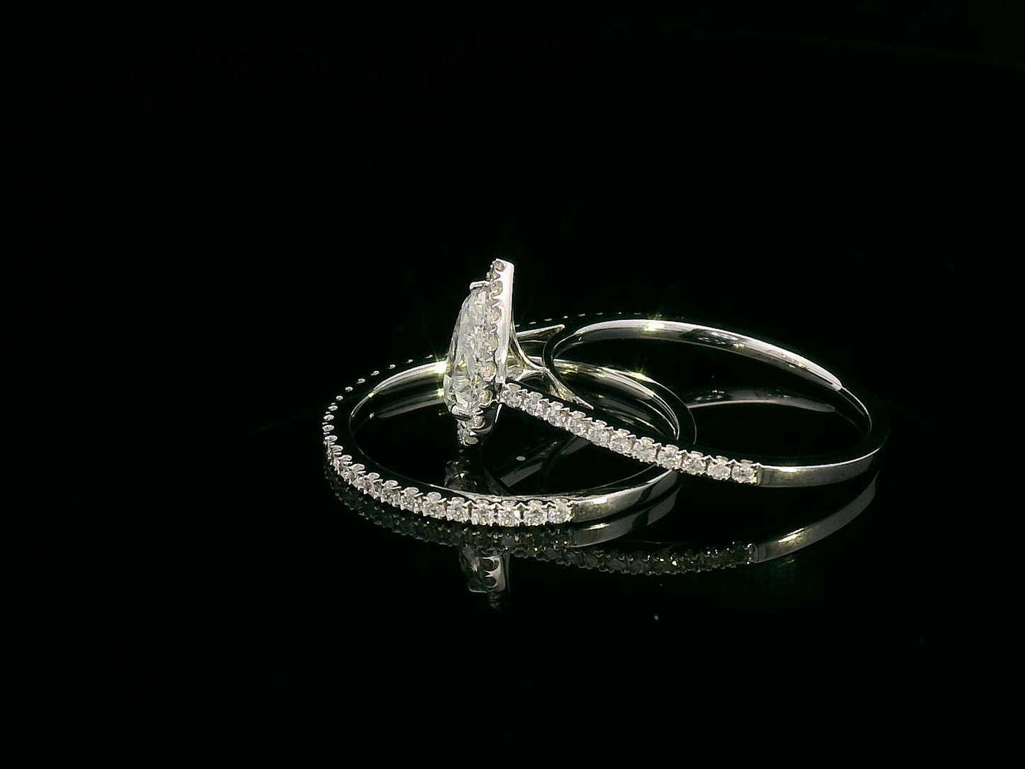 18K gold bridal ring set featuring a 0.91 carat pear-shaped diamond with halo and pavé-set accent diamonds on both engagement ring and matching wedding band