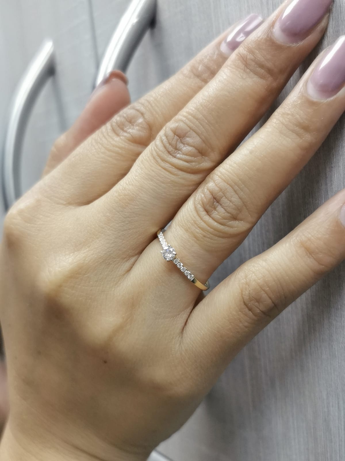 18K yellow gold ring with 0.18ct round center diamond and 10 smaller side diamonds set in a classic straight design.