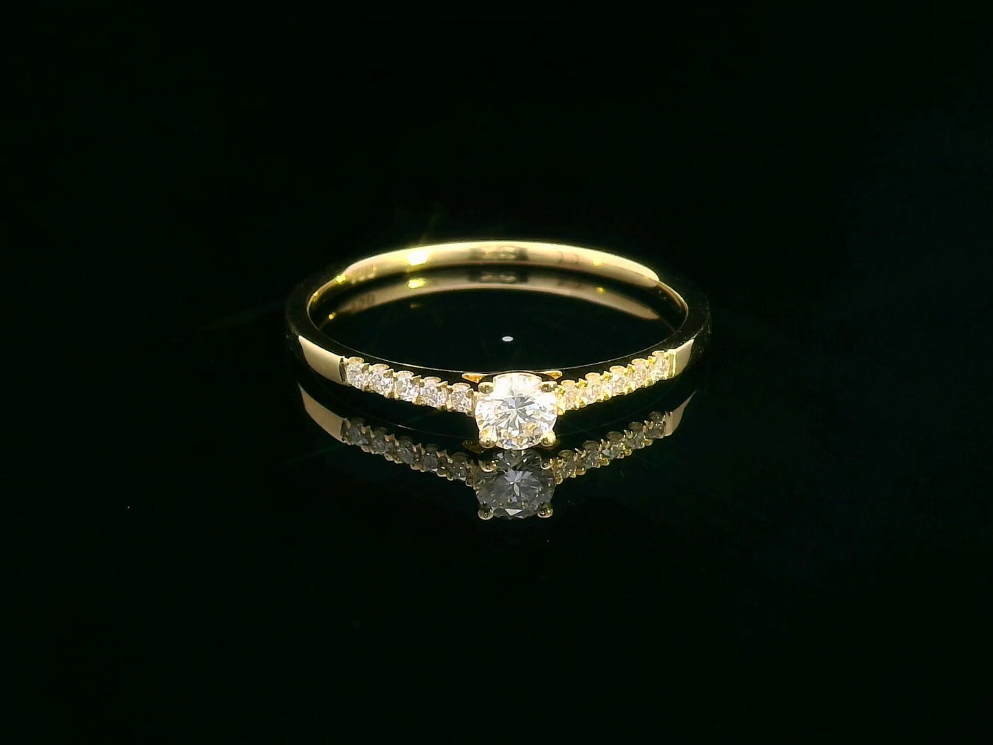 18K yellow gold ring with 0.18ct round center diamond and 10 smaller side diamonds set in a classic straight design.