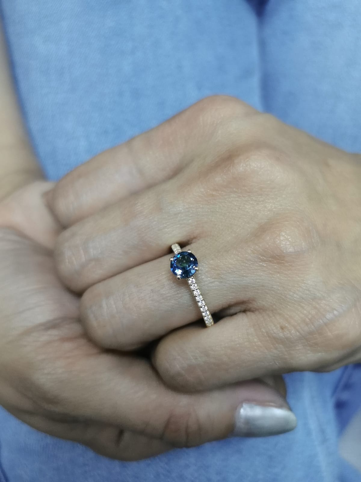 18K yellow gold ring with 0.93 carat round Blue Topaz center and 0.20 carat round diamond accents in fine prong setting along the band