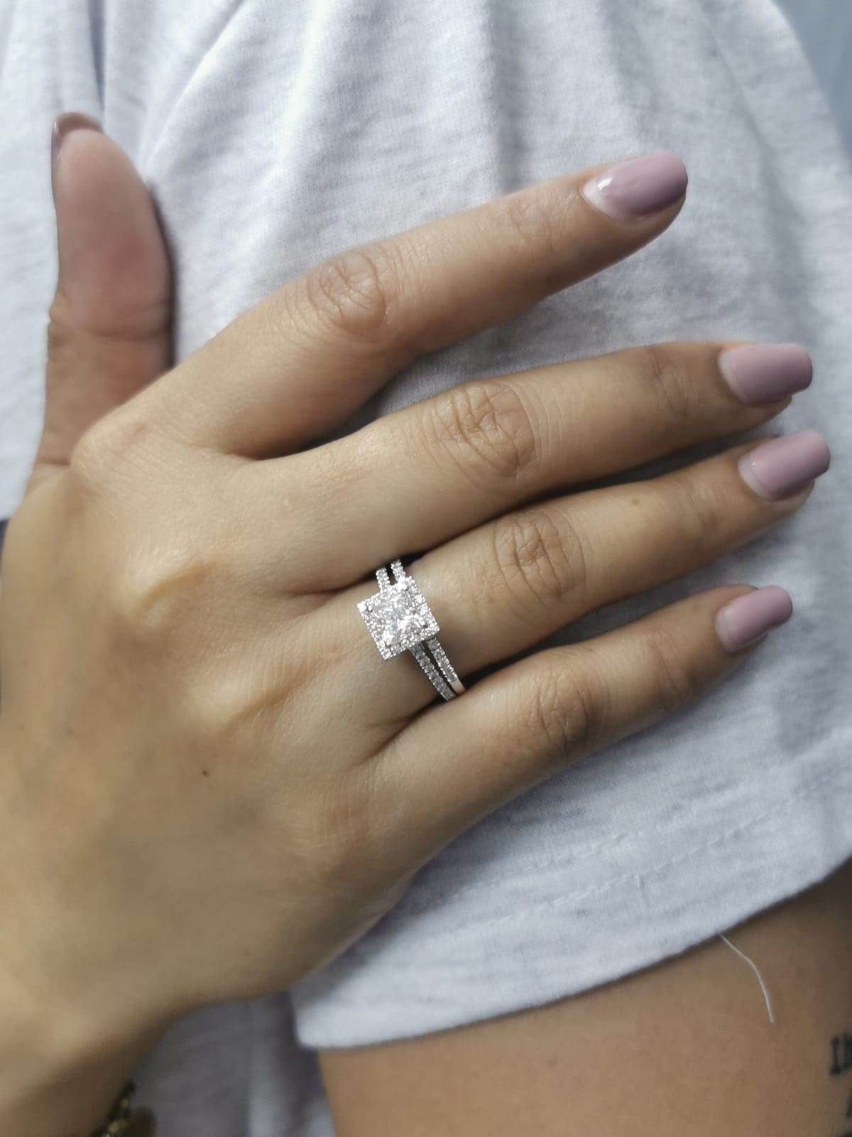 Princess cut diamond halo bridal set in 18K white gold with pavé-set engagement ring and matching band