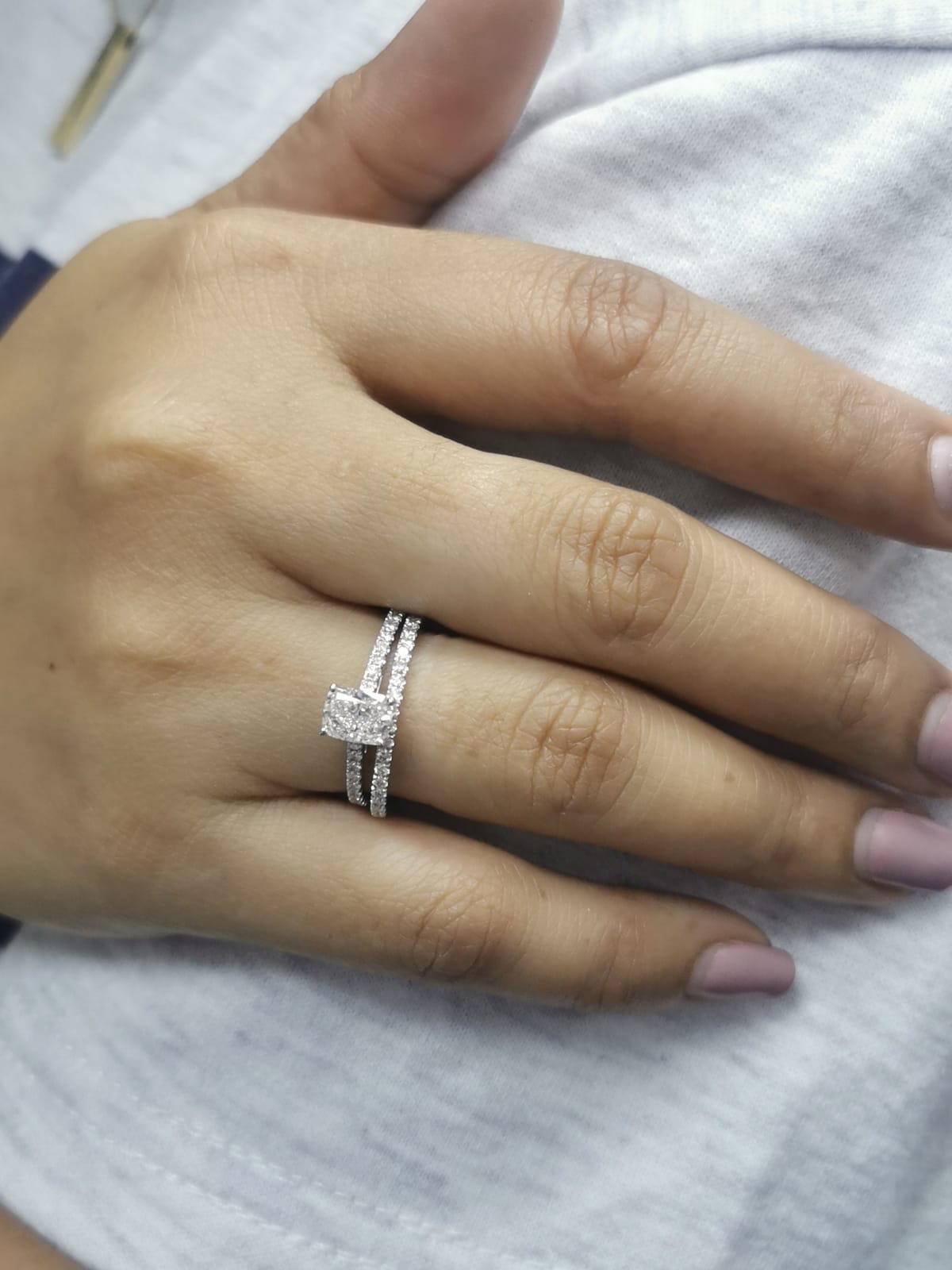 Cushion cut diamond bridal set in 18K white gold featuring pavé engagement ring and matching wedding band