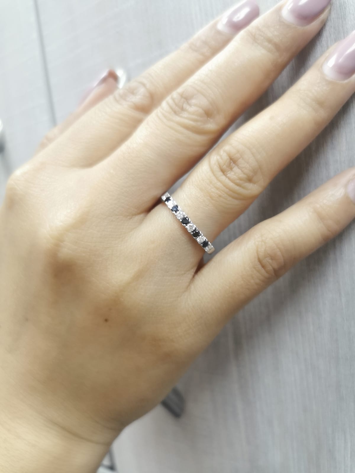 18K gold half eternity ring with alternating black and white round diamonds, minimalist band design.