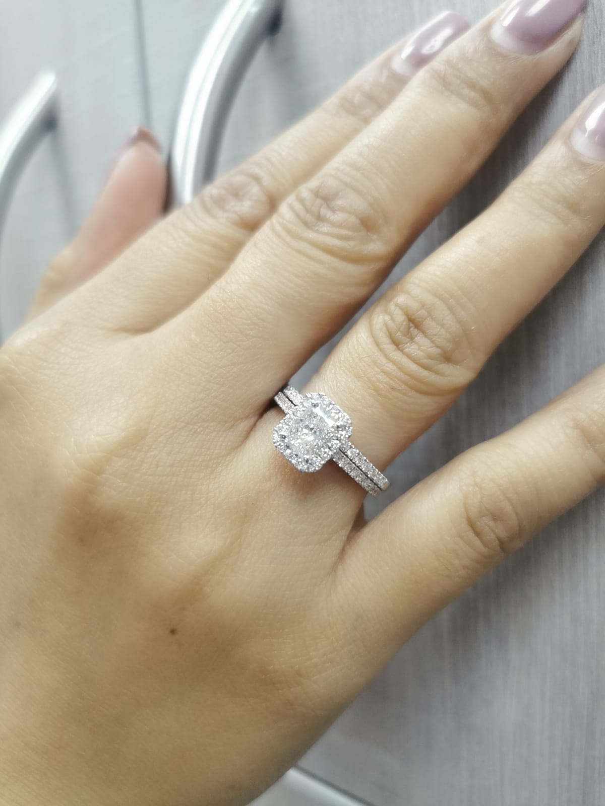 18K white gold bridal ring set with 1.50ct radiant-cut diamond, halo setting, pavé band, and matching half-eternity wedding band.