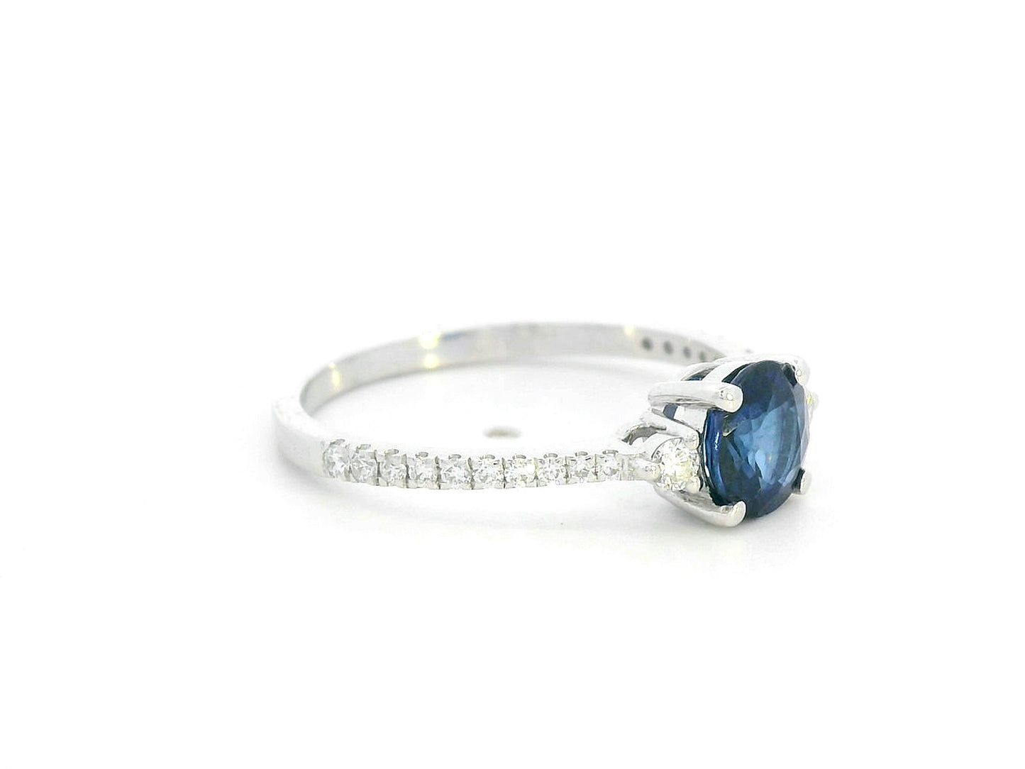 Blue sapphire ring in 18K white gold with flanking diamonds and pavé diamond band