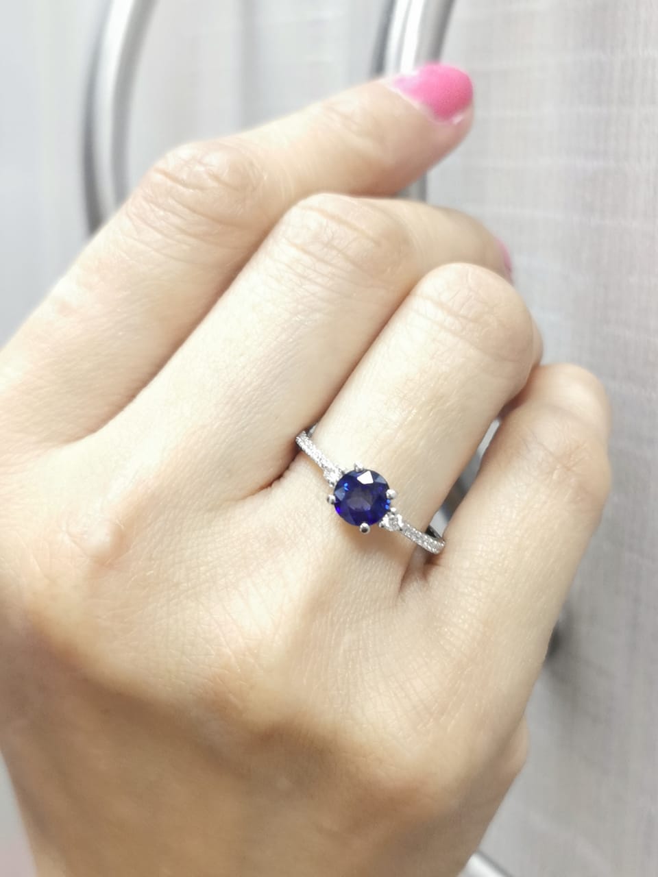 Blue sapphire ring in 18K white gold with flanking diamonds and pavé diamond band