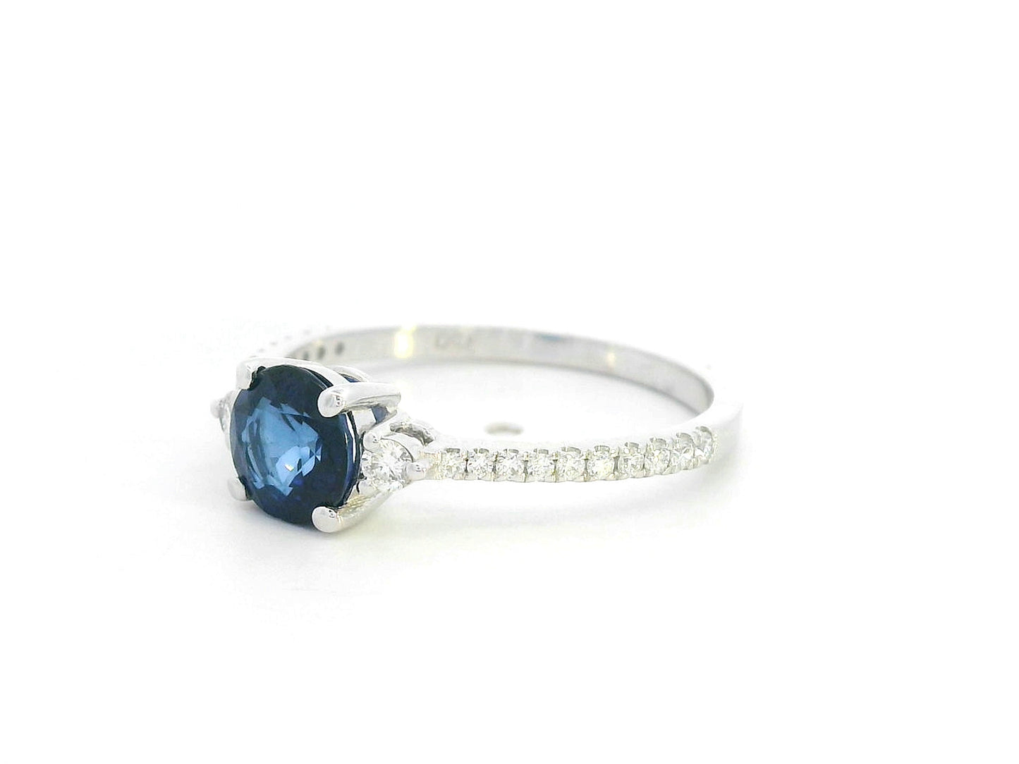 Blue sapphire ring in 18K white gold with flanking diamonds and pavé diamond band