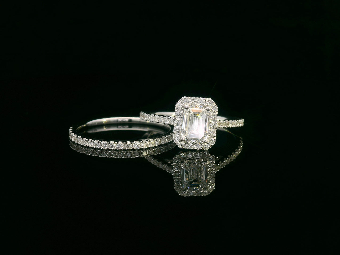 18K white gold bridal set with emerald-cut 1.00ct diamond, halo engagement ring, and half-eternity diamond band
