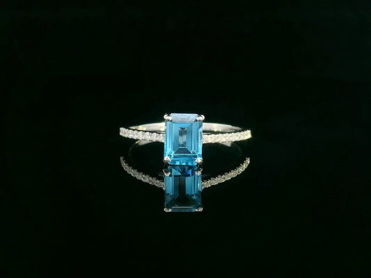Emerald-cut blue topaz ring in 18K white gold with diamond-accented band.
