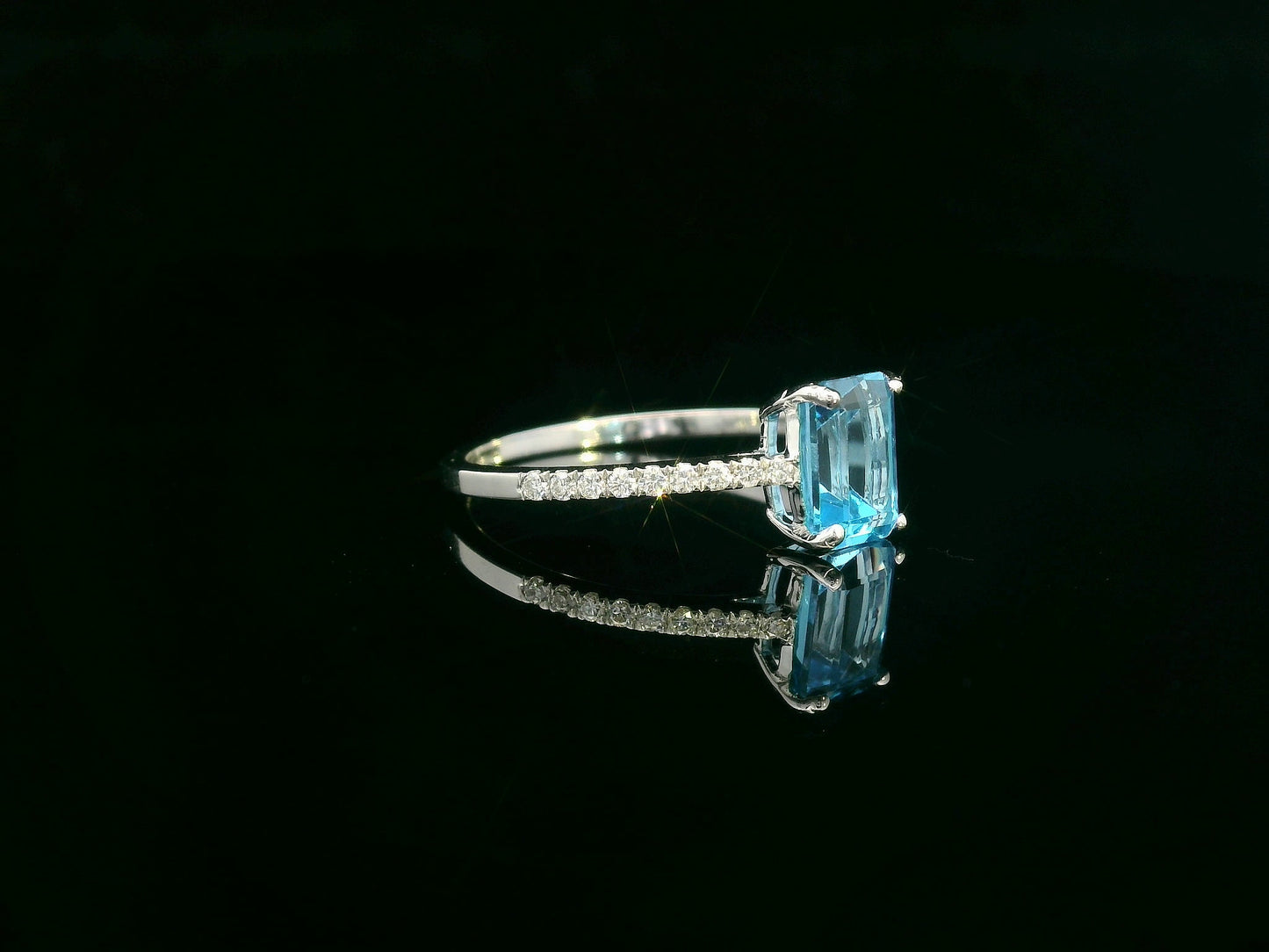 Emerald-cut blue topaz ring in 18K white gold with diamond-accented band