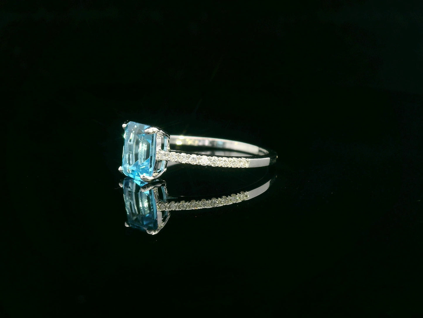 Emerald-cut blue topaz ring in 18K white gold with diamond-accented band