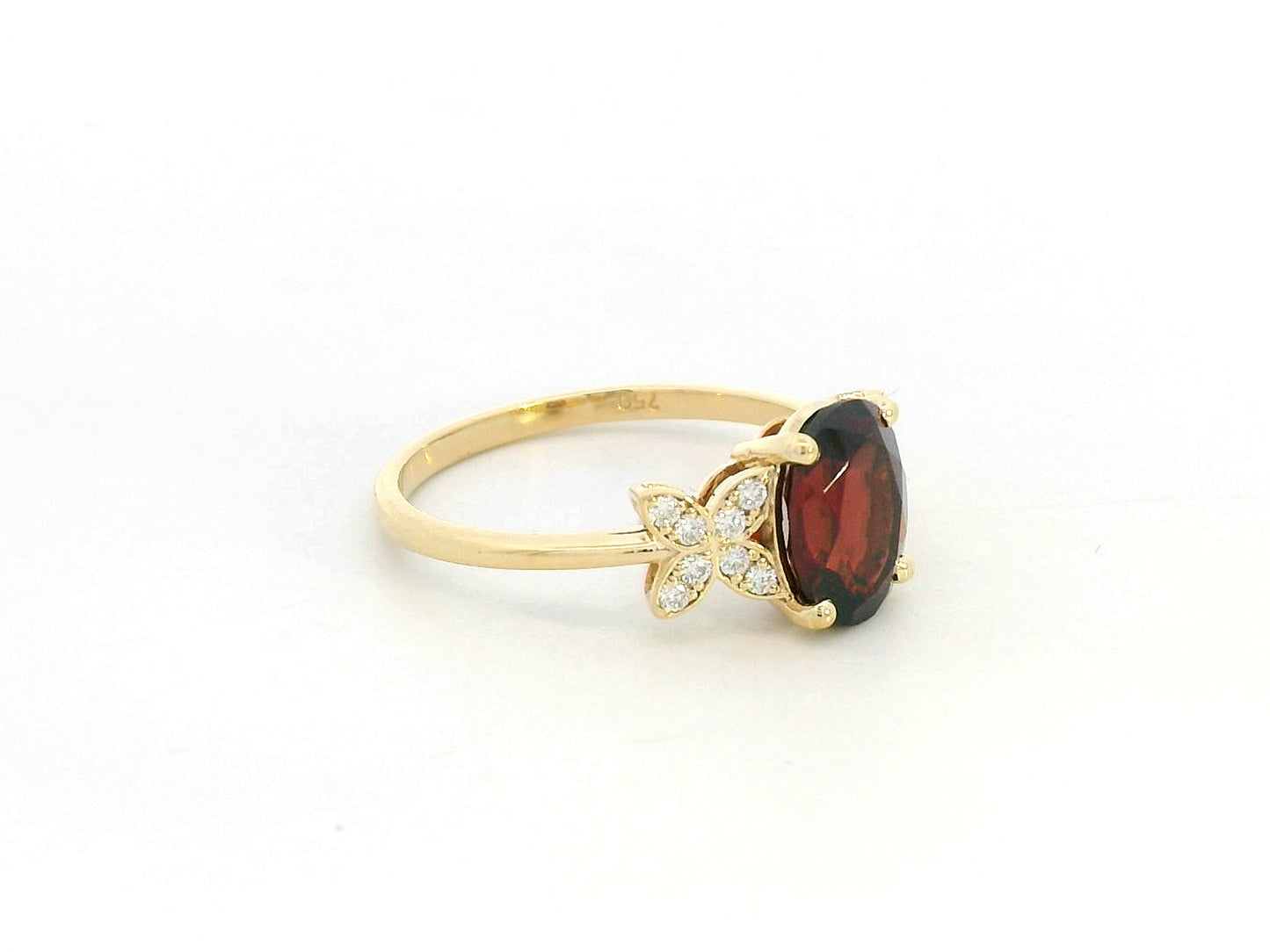 Side view showing four-prong garnet setting and delicate diamond clusters