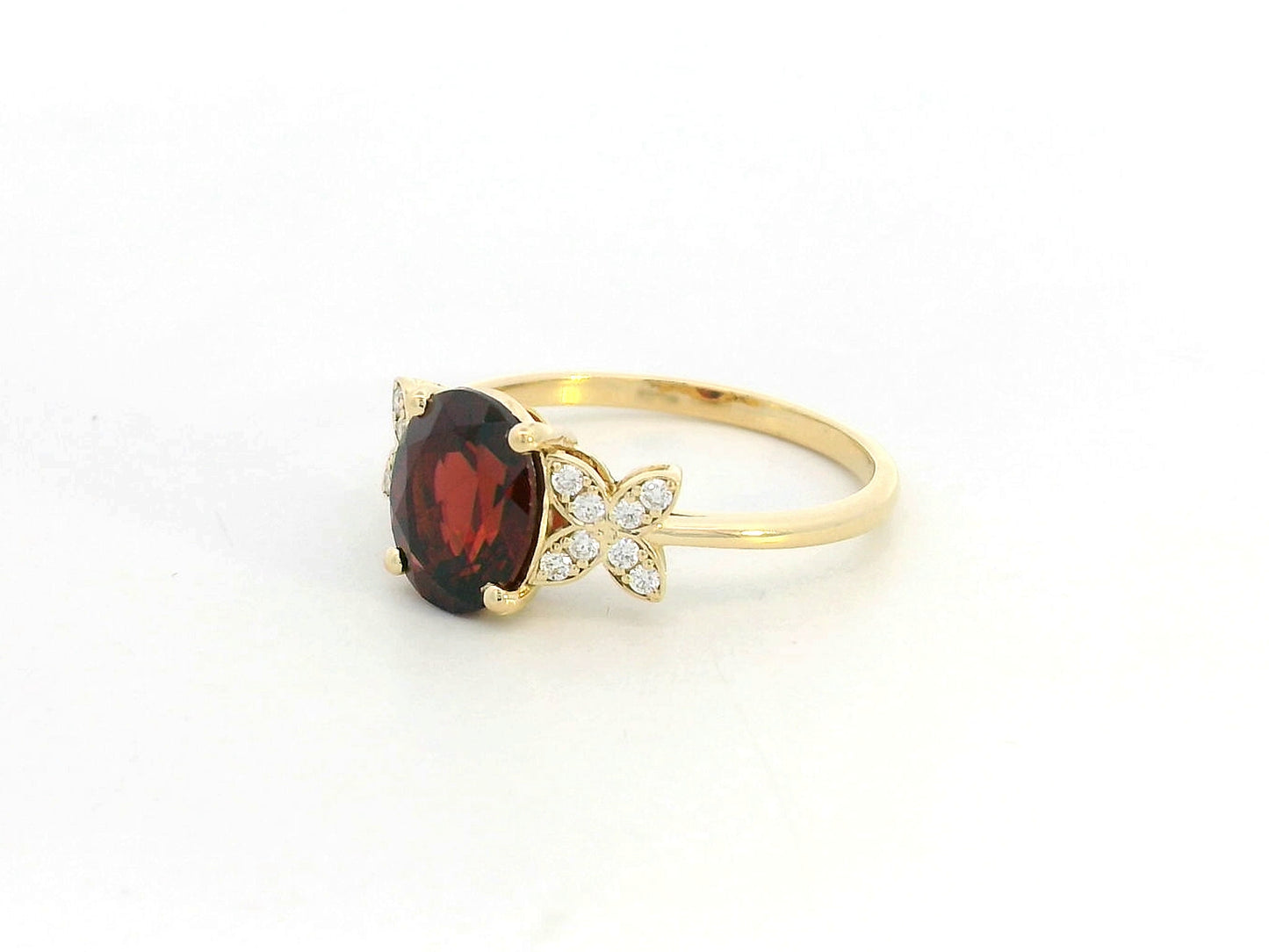 Side view showing four-prong garnet setting and delicate diamond clusters